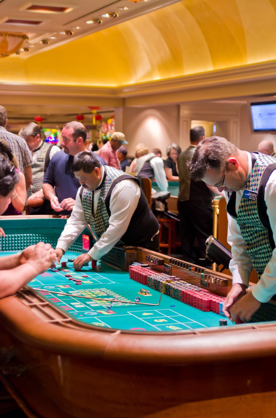 A real photo of a craps table at Harrah's Las Vegas, with a casino dealer standing at the rail and the table layout visible