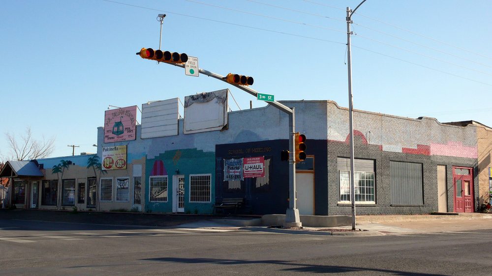 A colorfully painted, weathered storefront on 3rd Street in downtown Pecos, Texas, at the corner where I-20 approaches its merge with I-10