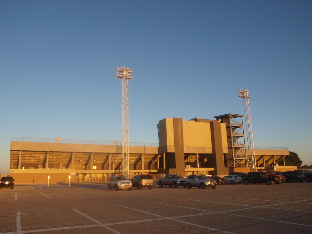 Ratliff Stadium in Odessa, Texas at sunset, an empty parking lot in front of the stadium's stands and stadium lights