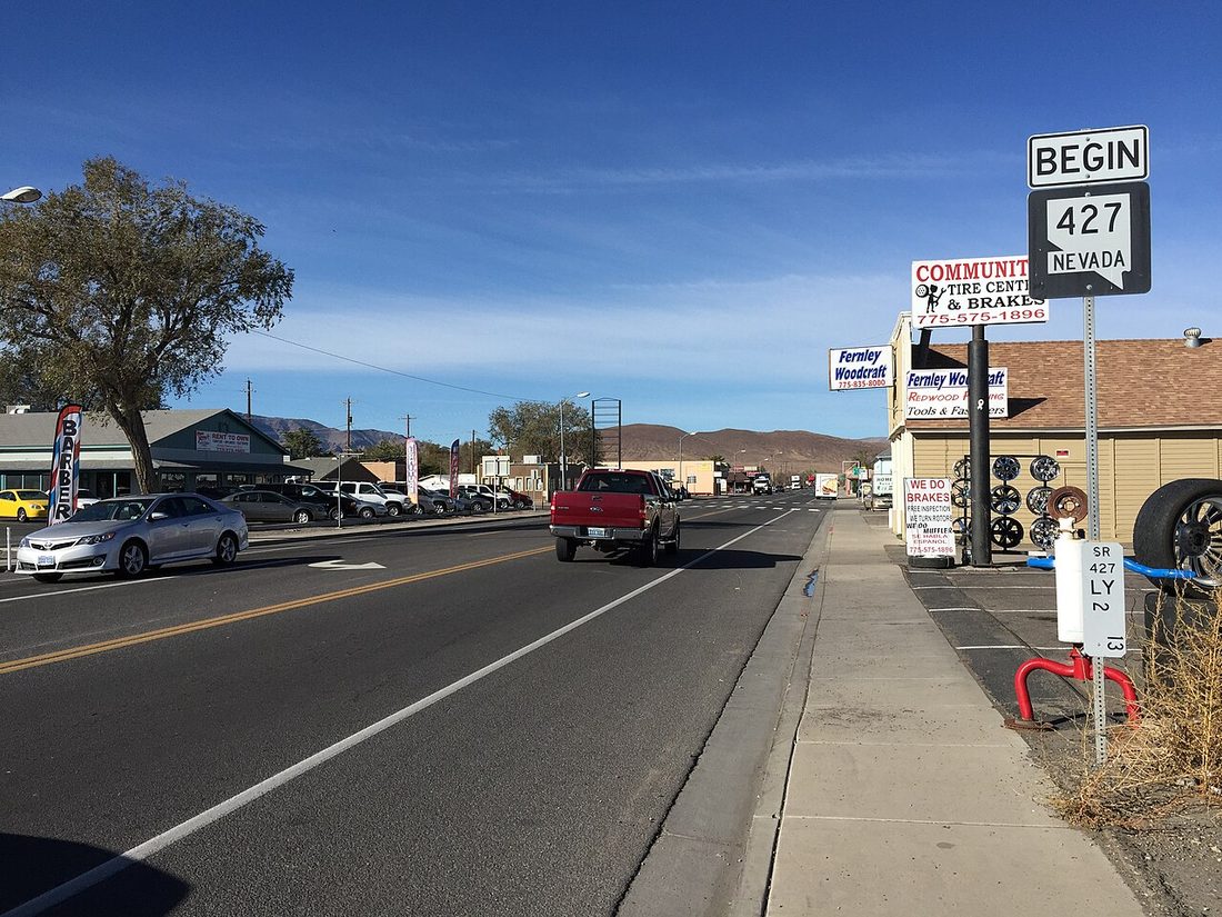 Main Street in Fernley, Nevada, showing storefronts, a red pickup truck, and a Nevada State Route 427 sign in the foreground