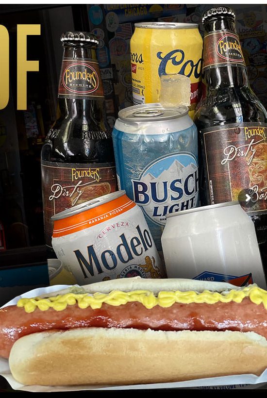 A quarter-pound all-beef hot dog with mustard at Stage Door Casino, in front of bottles and cans of Founders, Coors, Busch Light, and Modelo beer