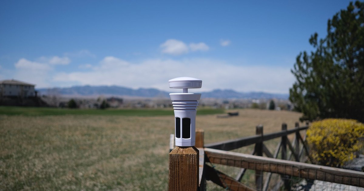 Tempest Weather Station mounted on a wood fence post with Colorado prairie and mountains in the background