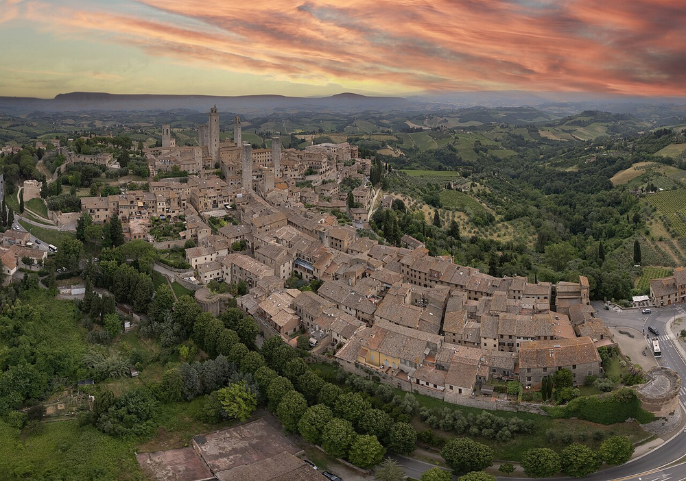 Wikipedia's San Gimignano article showing an aerial photo of the walled medieval town's tower skyline at sunset