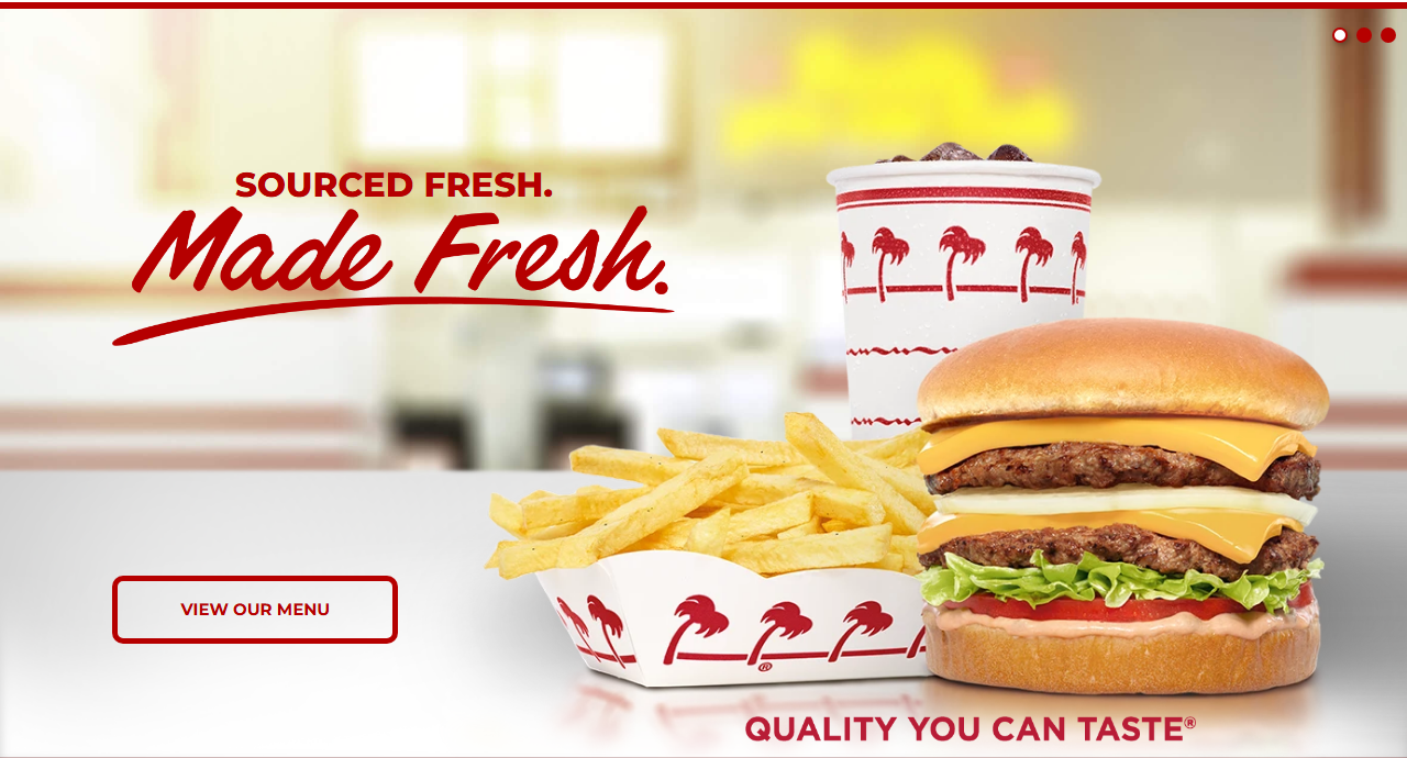In-N-Out Burger's official homepage hero, showing a Double-Double cheeseburger with fries and a drink in the chain's signature red-and-white palm-tree packaging