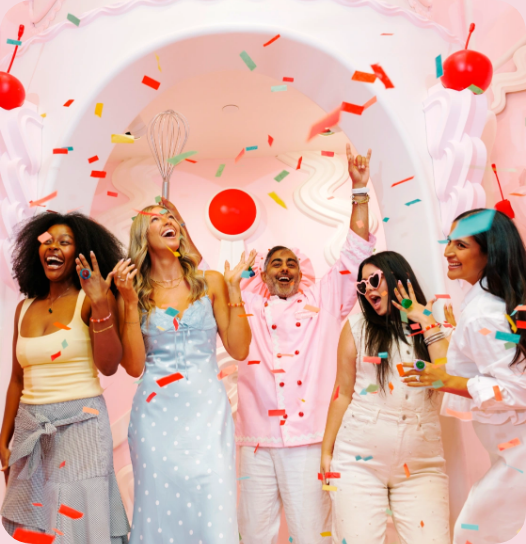 Museum of Ice Cream's official Las Vegas homepage showing a group of visitors cheering under a shower of confetti inside a pink, whisk-and-cherry-decorated archway